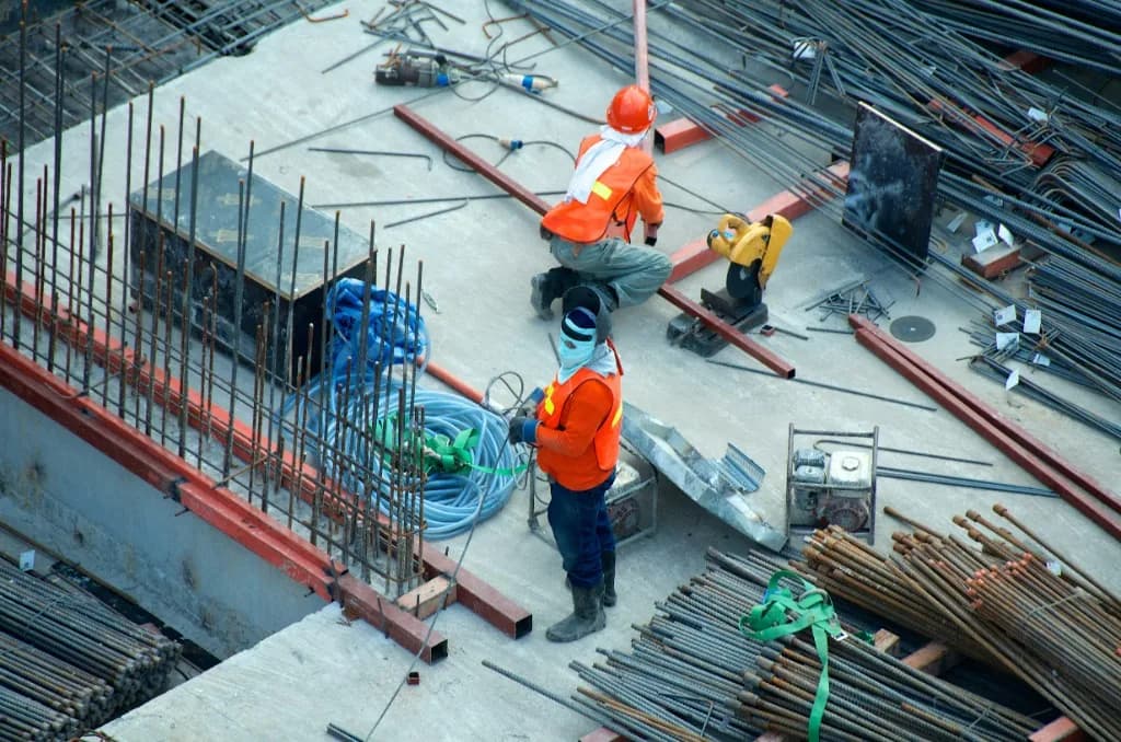 Workers tying rebar on a commercial concrete slab from above