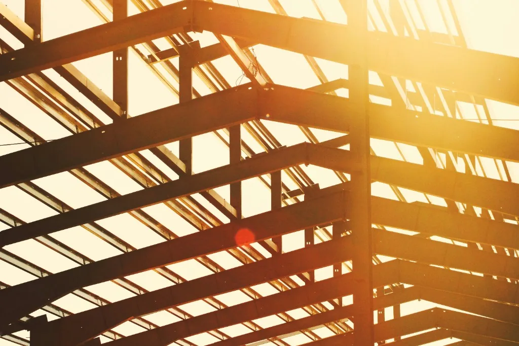 Steel building frame silhouetted against golden construction-site sunlight