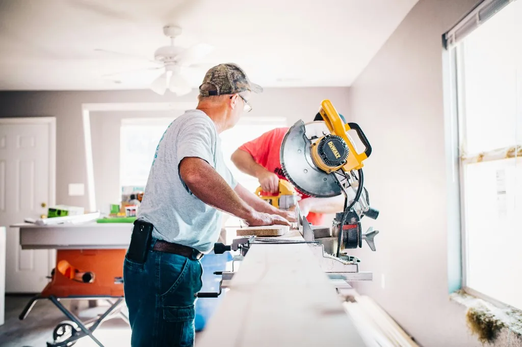 Carpenters cutting lumber with a miter saw on an active residential job site